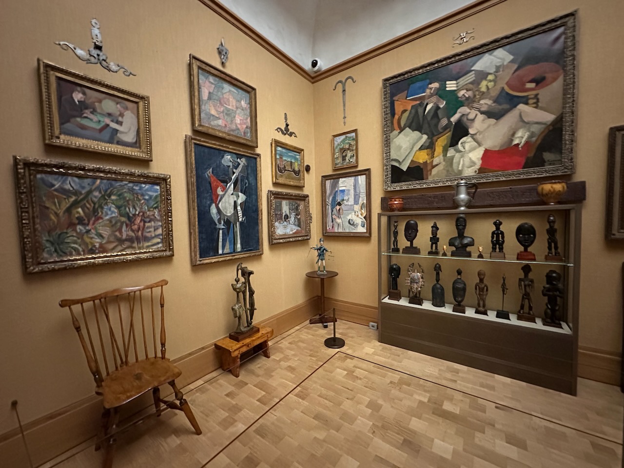 Varied artwork on walls and in display cases including paintings, sculptures, and furniture.