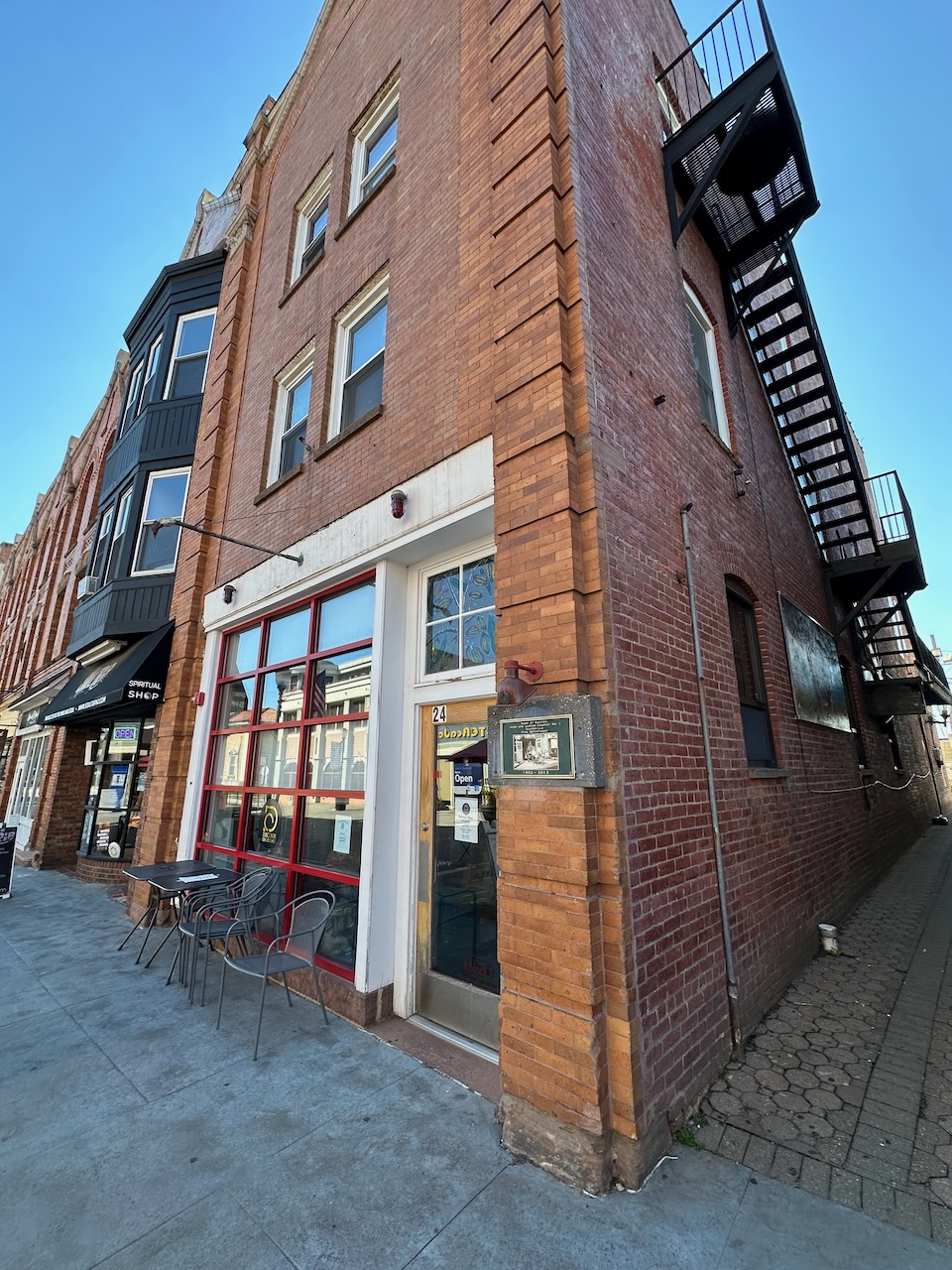 Exterior of brick four-story building with fire escape on side of building. 