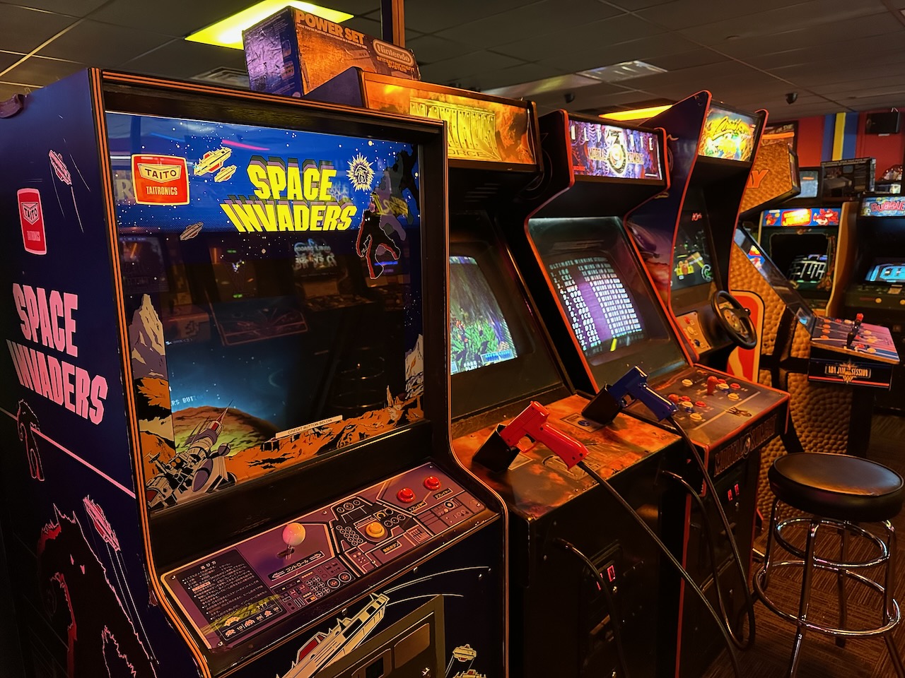 Row of video game cabinets including Space Invaders.