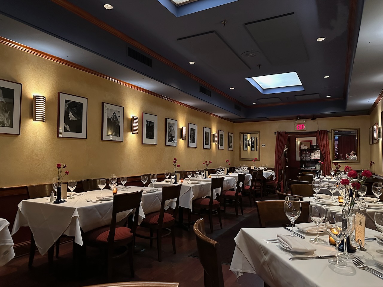 Interior of restaurant, with rows of tables covered in white tablecloths on both sides of dining room.