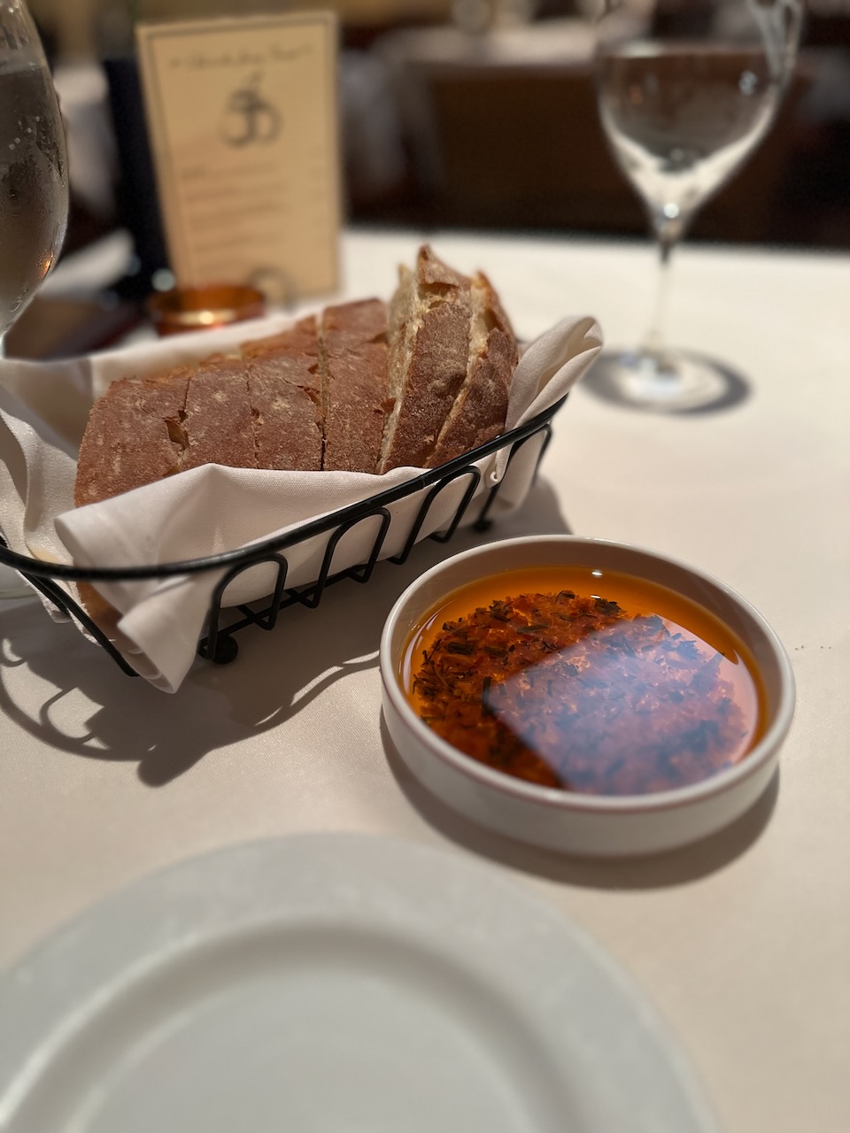 Bread with olive oil dipping sauce on table with white tablecloth.