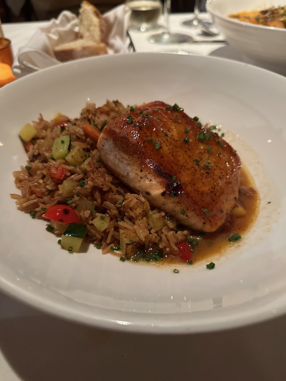 Grilled salmon on a bed of fried rice, on a white plate. 