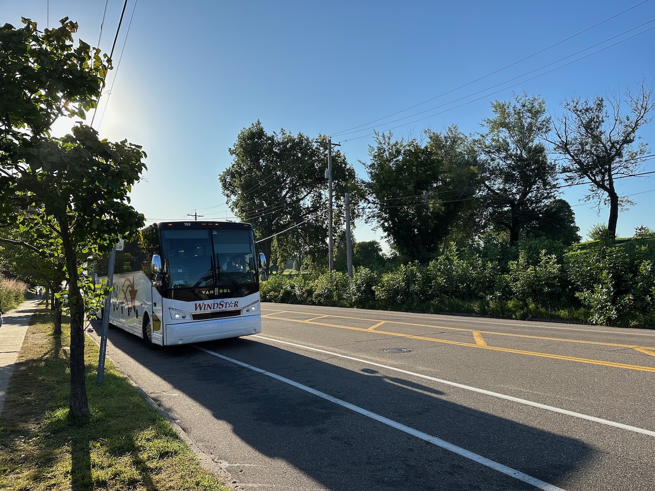 View of coach bus parked along tree-lined street.
