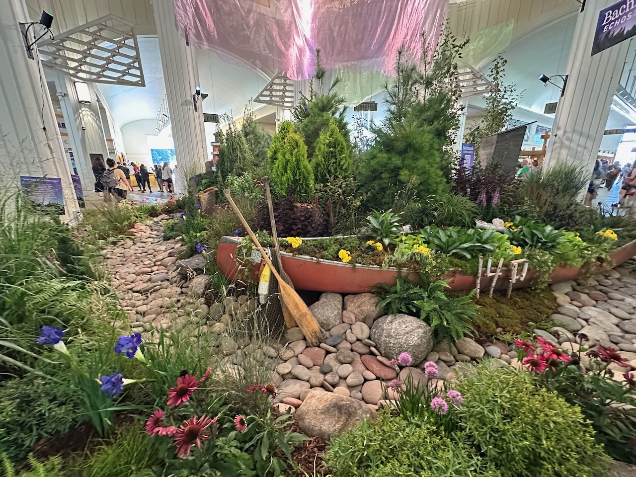 Centerpiece with canoe, surrounded by different plants and flowers.
