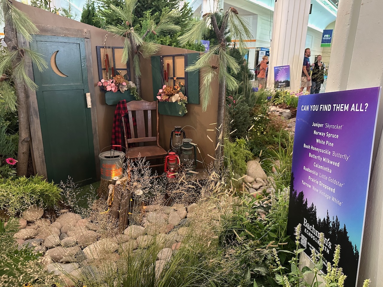 Floral centerpiece with model of log cabin, surrounded by plants from Minnesota.
