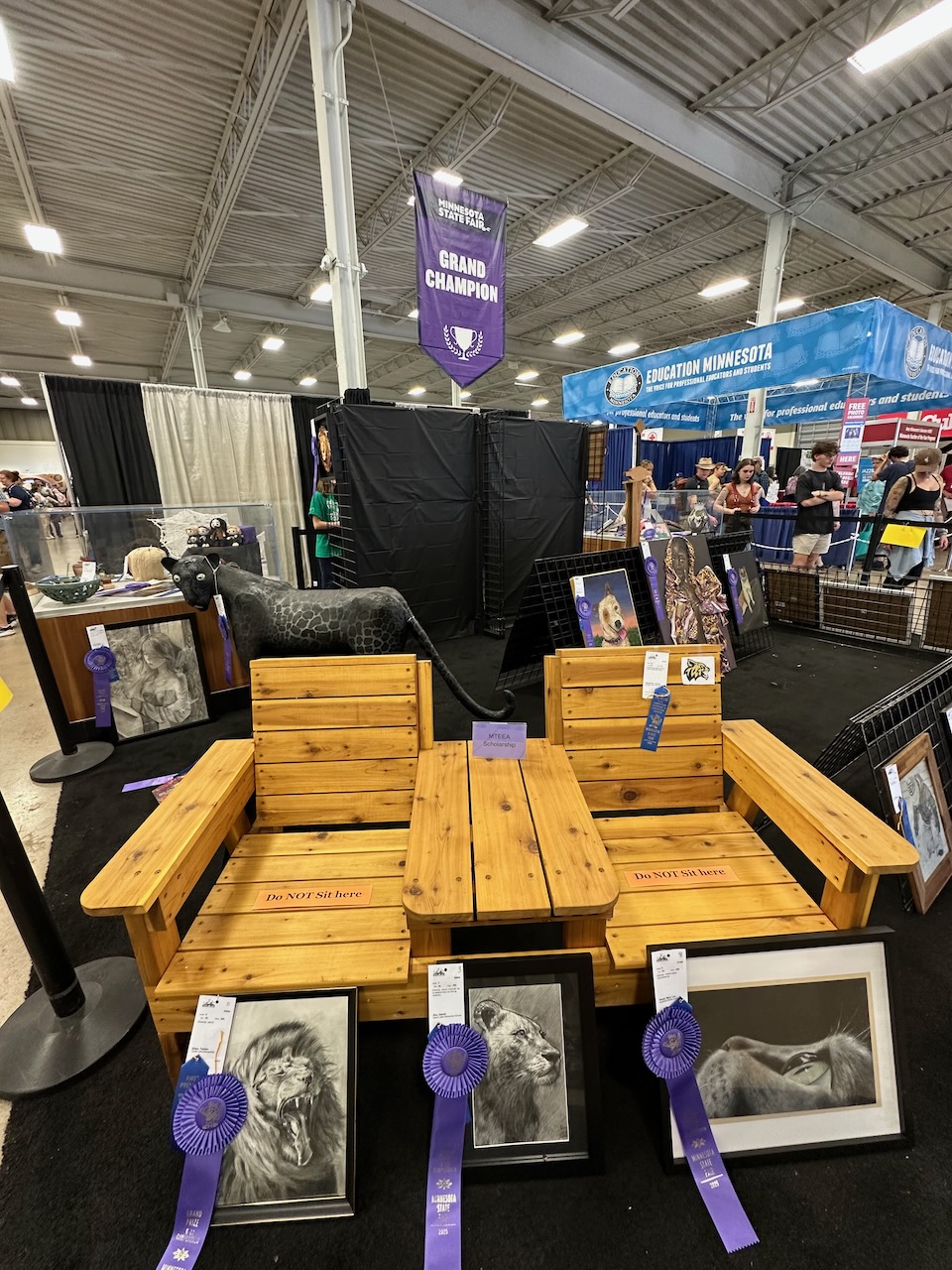 Two wooden chairs on display, with award winning photographs near them.