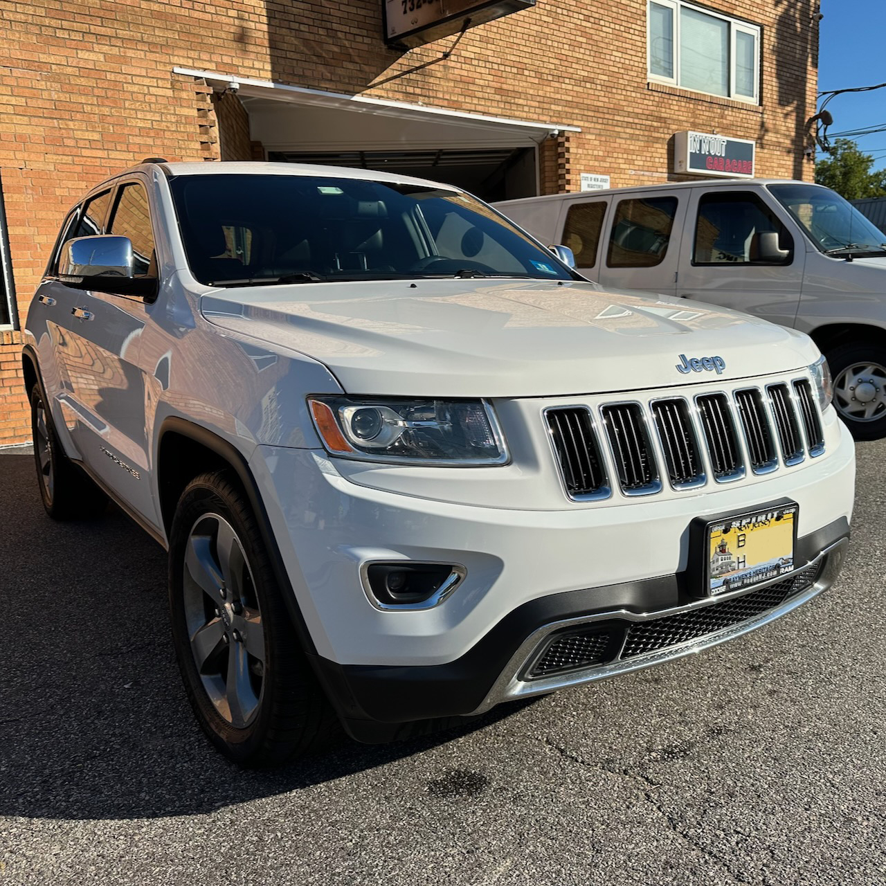 2014 Jeep Grand Cherokee parked in front of auto body shop. 