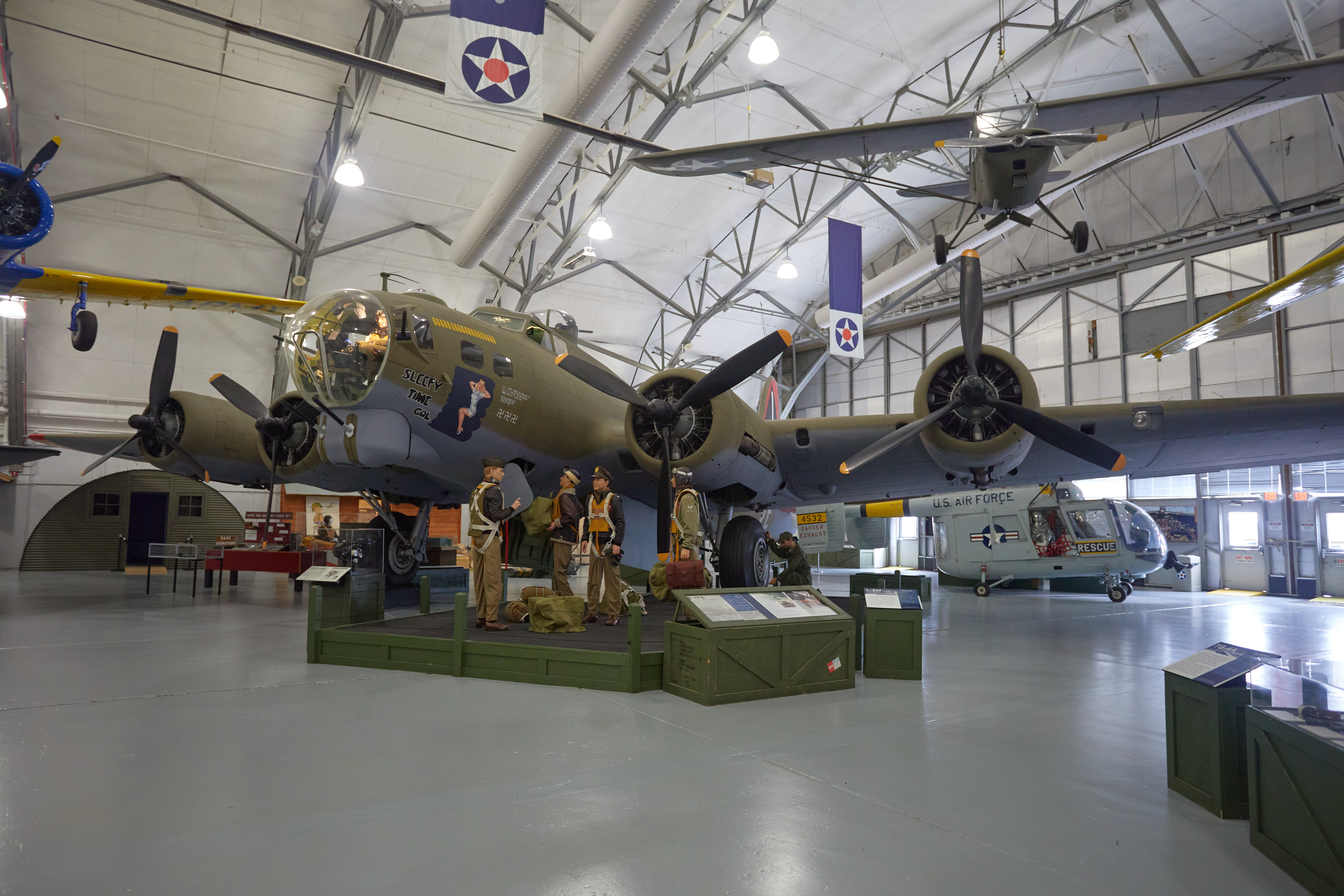 B-17G Flying Fortress on display in hangar, with mannequins dressed as flight crew in foreground.