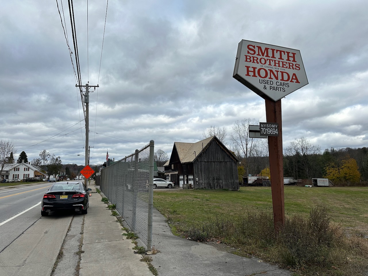2020 Acura TLX parked on side of road beside sign for Smith Honda Used Cars and Parts.