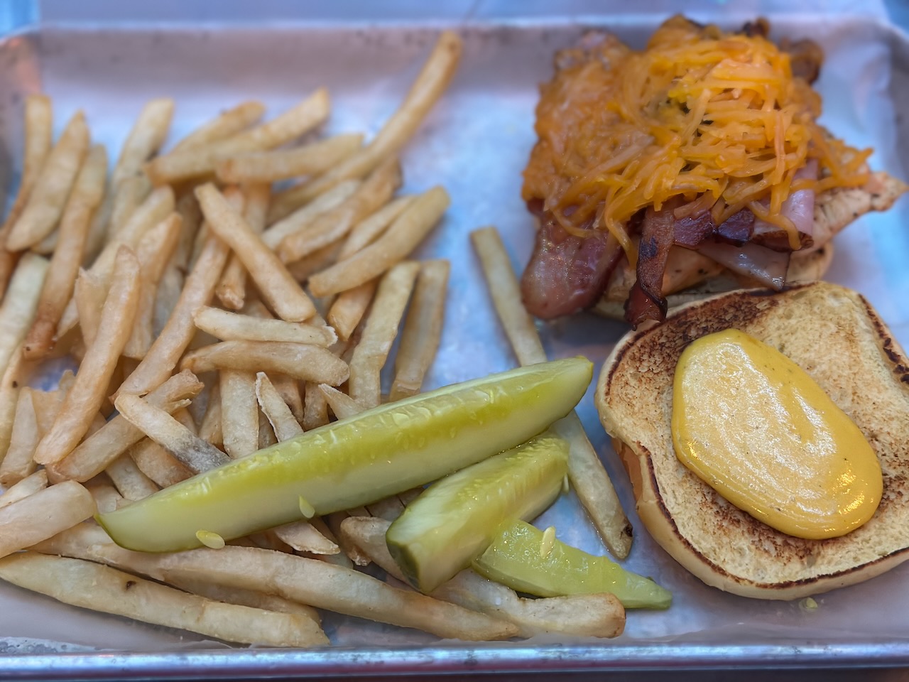 Chicken sandwich and fries on silver tray.