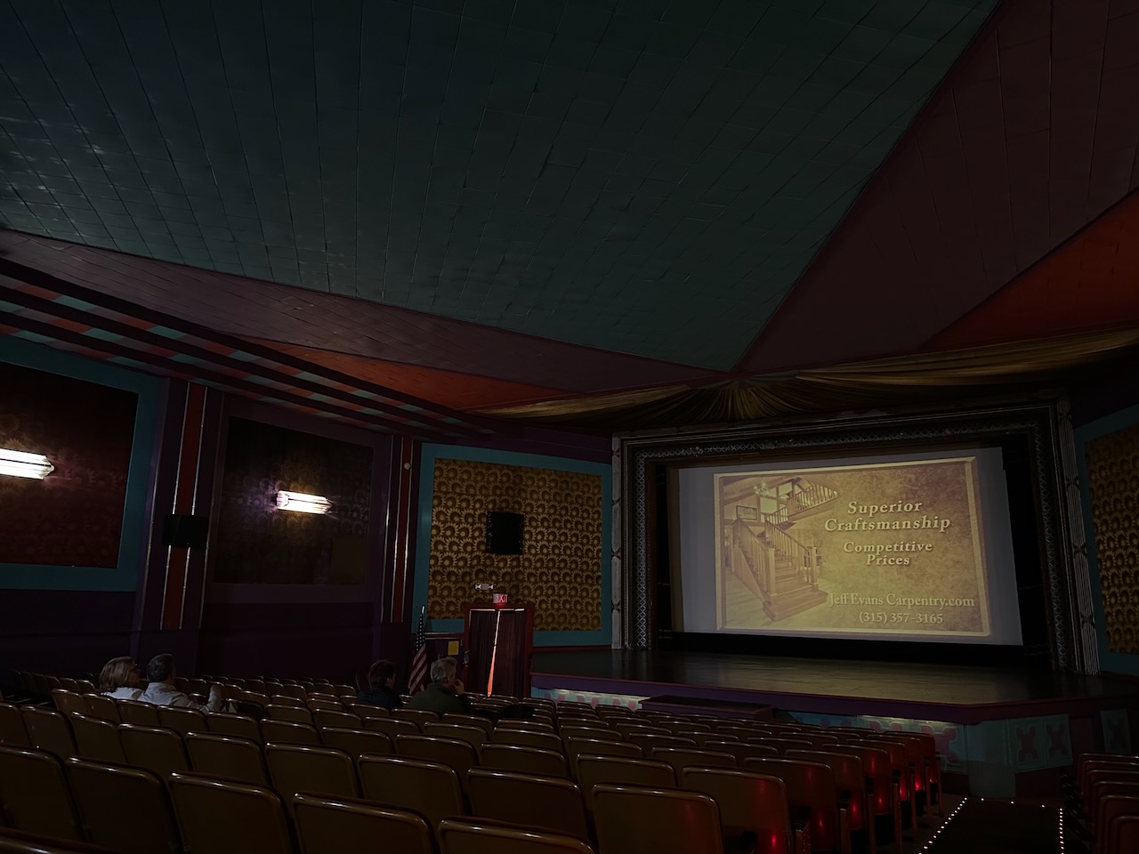 Interior of theater, with some people in audience. 