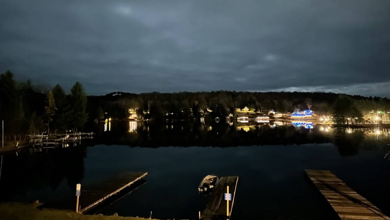 View of Old Forge Pond at night, with houses across the pond lit up.