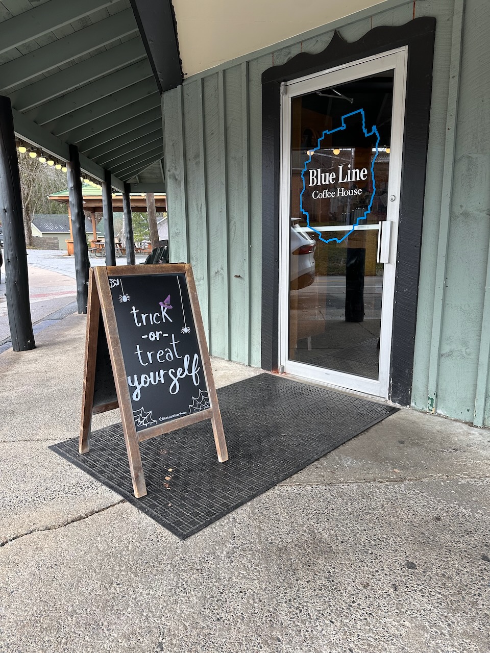 Front door of Blue Line Coffee House, with sign in front of door on chalkboard.