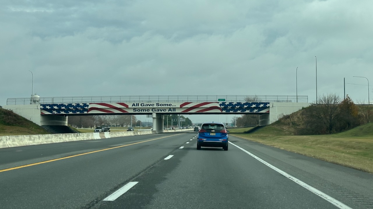 Bridge overpass painted in American flag colors with words ALL GAVE SOME SOME GAVE ALL painted on bridge as well. 