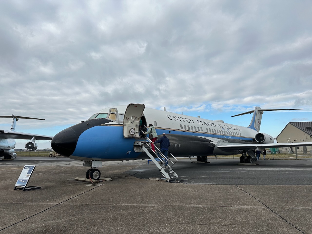 VC-9C jet plane with door open. People are ascending stairs into plane. 