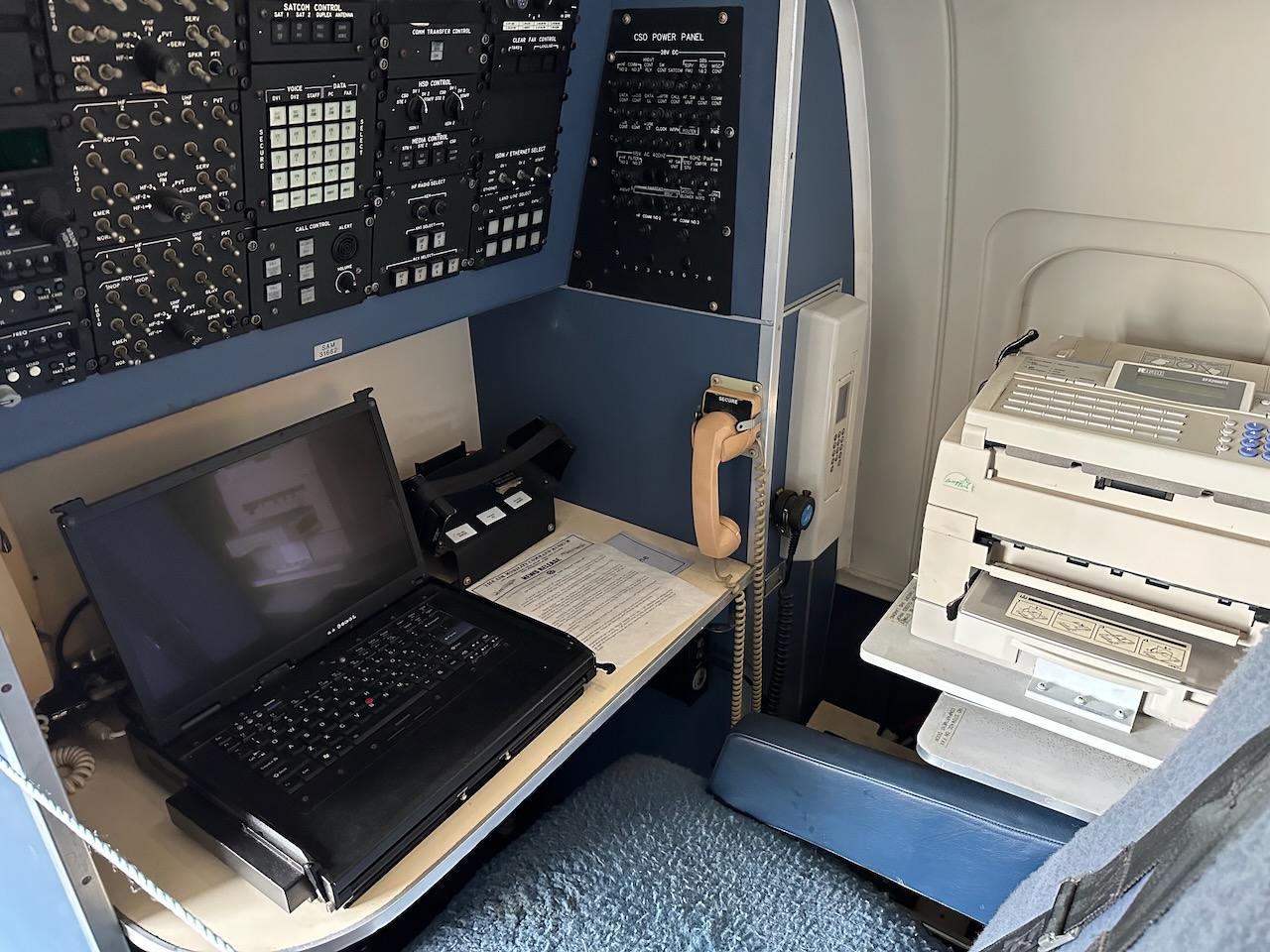 Laptop and fax machine in small compartment on plane. 