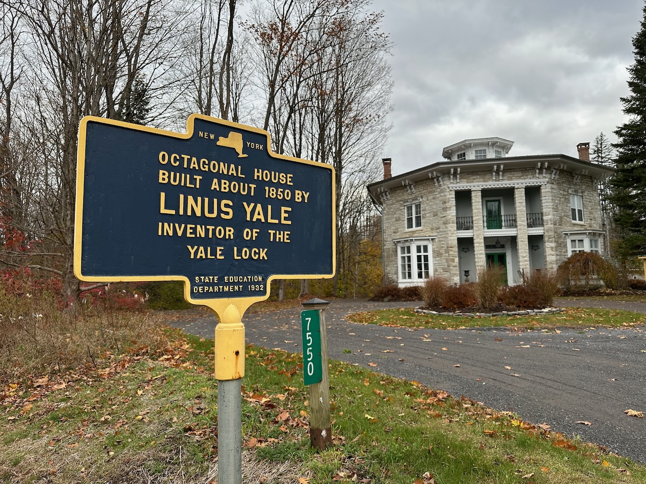 Exterior of stone Octagon House, with blue sign with information about house. 