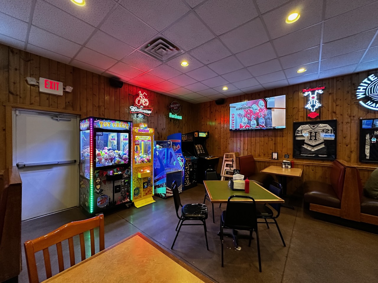 View of saloon with open tables, arcade games, and neon signs on walls.