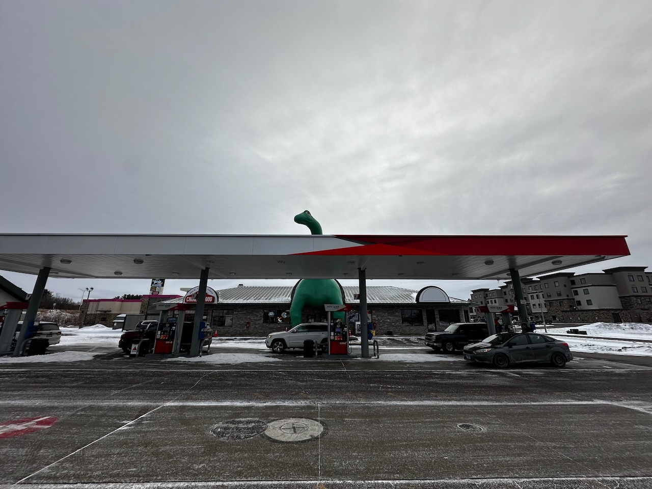 Sinclair gas station with life-size dinosaur statue behind station.