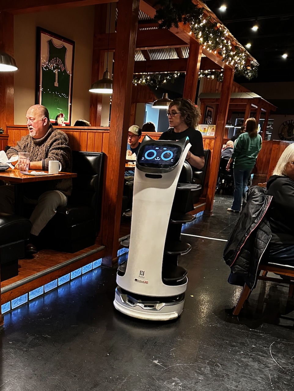 Robot driving across floor of restaurant.