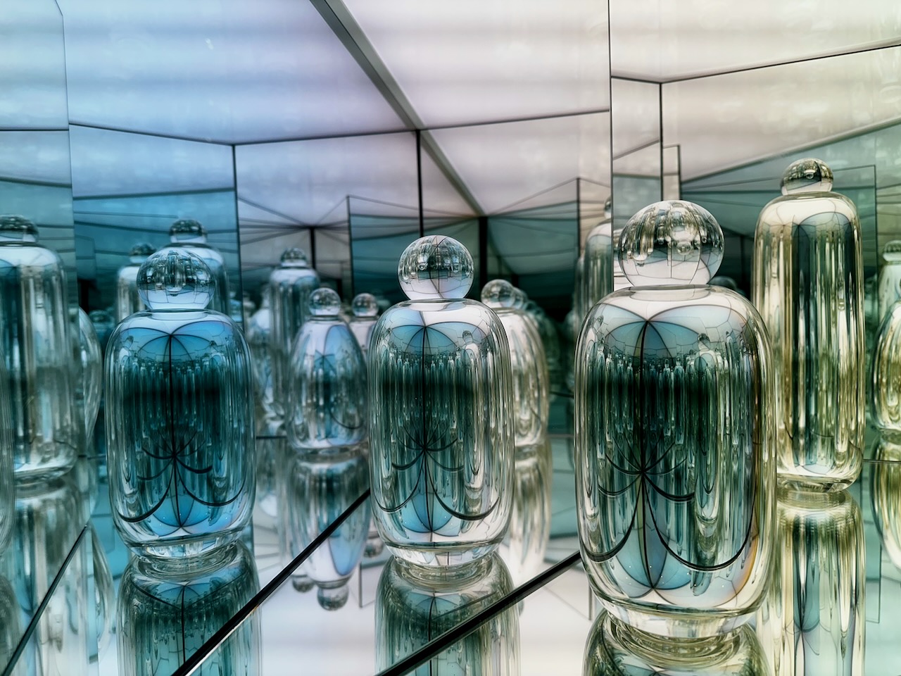 Display of glass objects in reflecting mirror box.