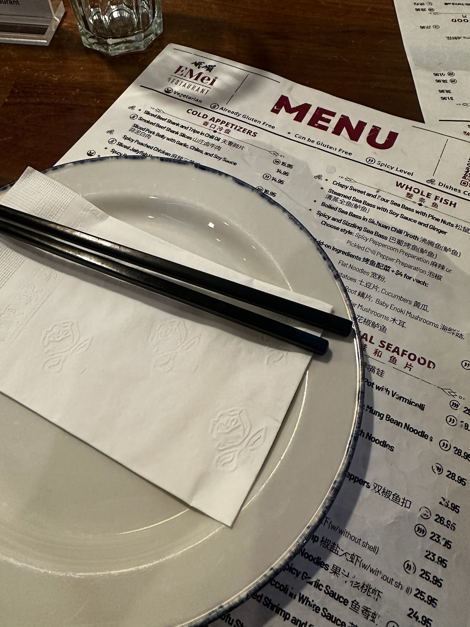 Plate, chopsticks, menu, and beverages on table.