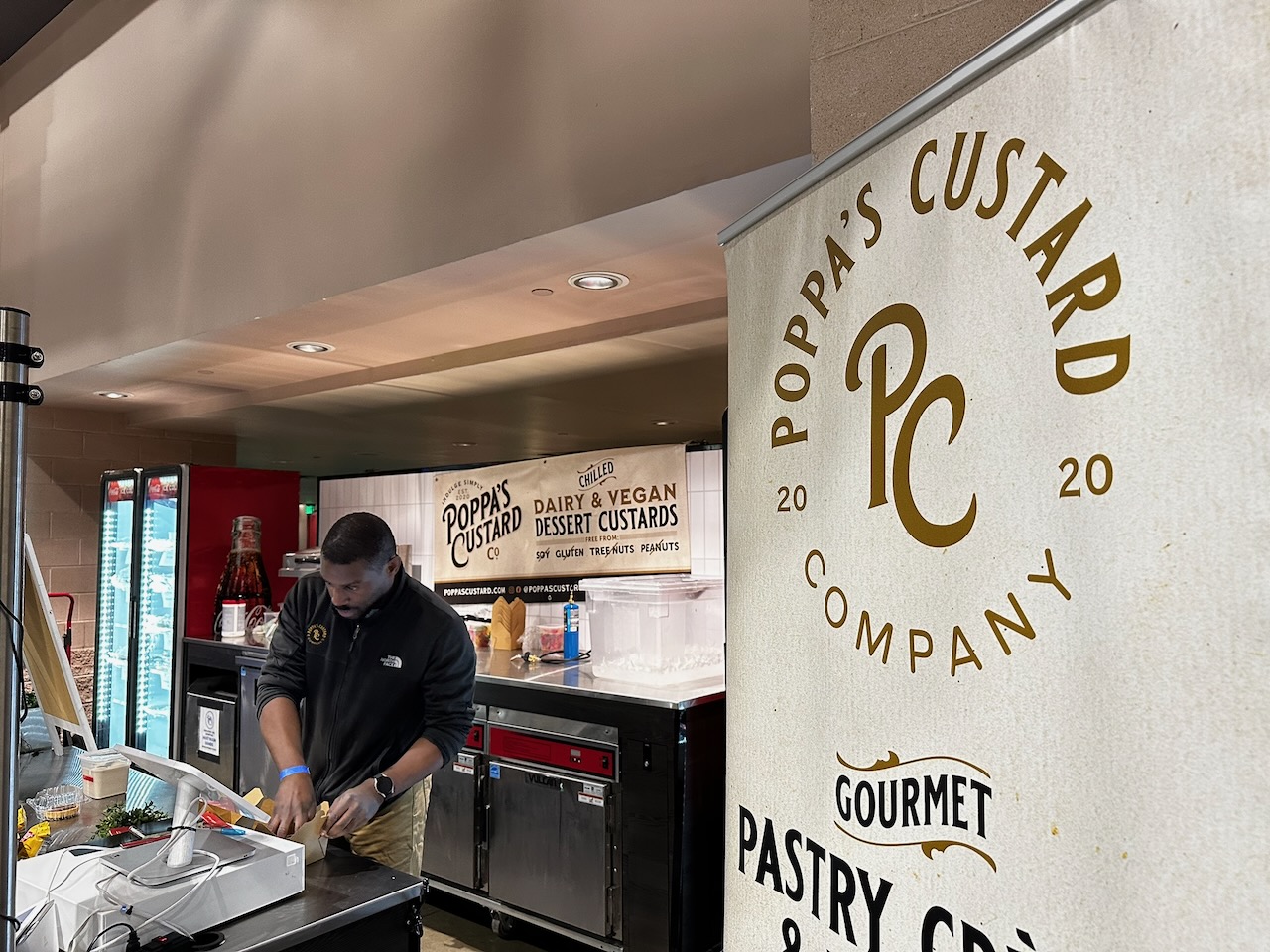 Poppy’s Custard dessert stand, with man working behind counter of store.