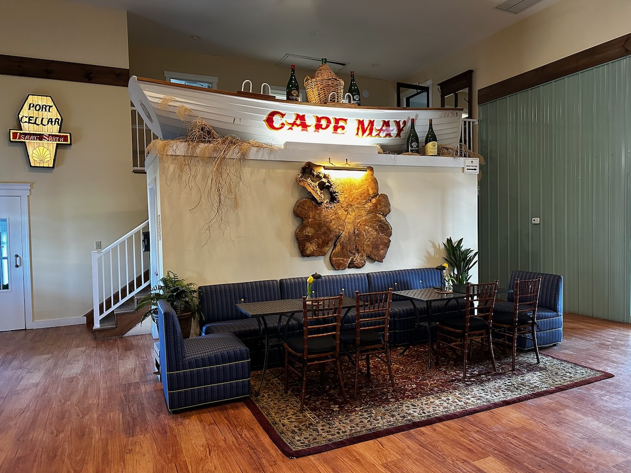 Winery with lifeboat with words CAPE MAY on sides on top of wall. A sitting area is beneath it.