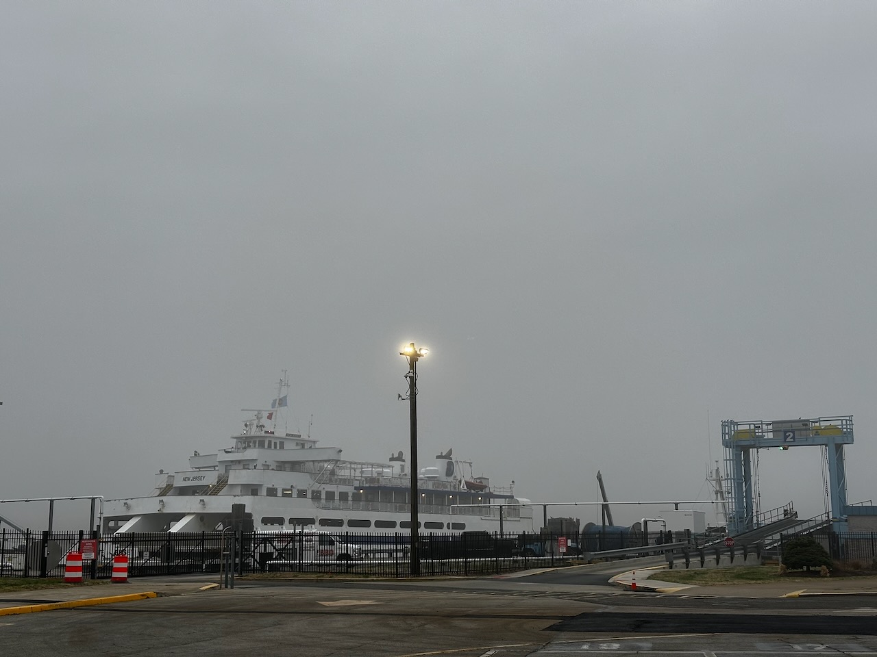Cape May-Lewes Ferry docked by ferry terminal on a cloudy and gray day.