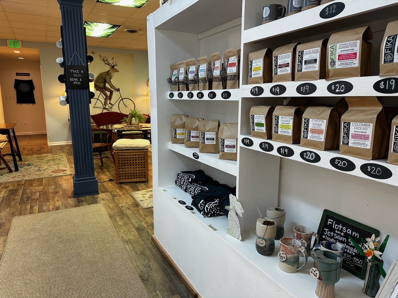 Interior of Fika Coffee Roasting, with bags on coffee on white shelves.