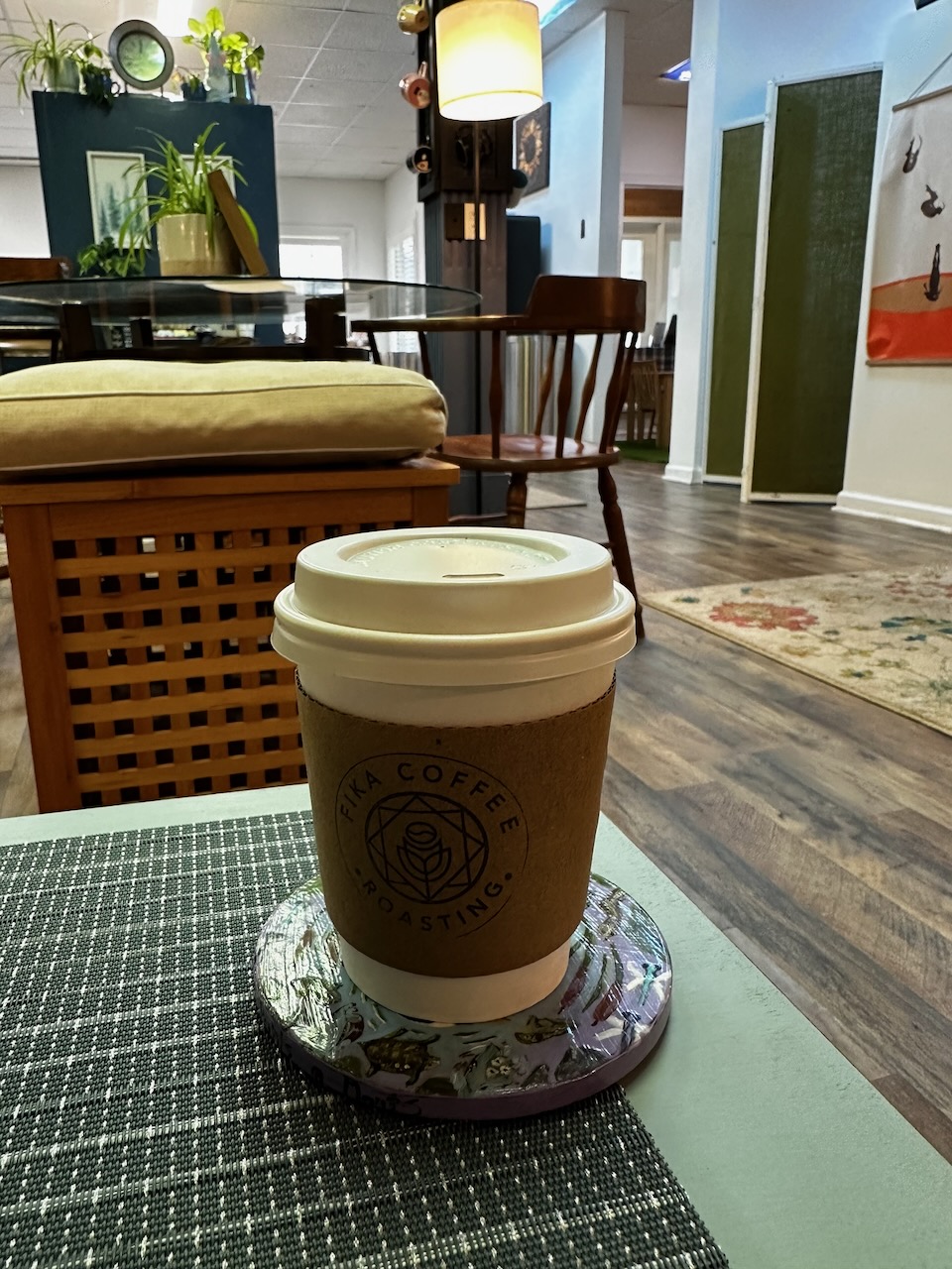 Cup of coffee on coaster on table in lounge area of coffee shop.
