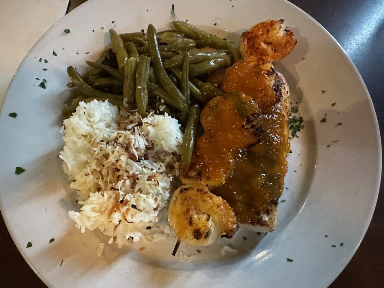 Jerk mahi and shrimp dinner with rice and green beans on white plate.