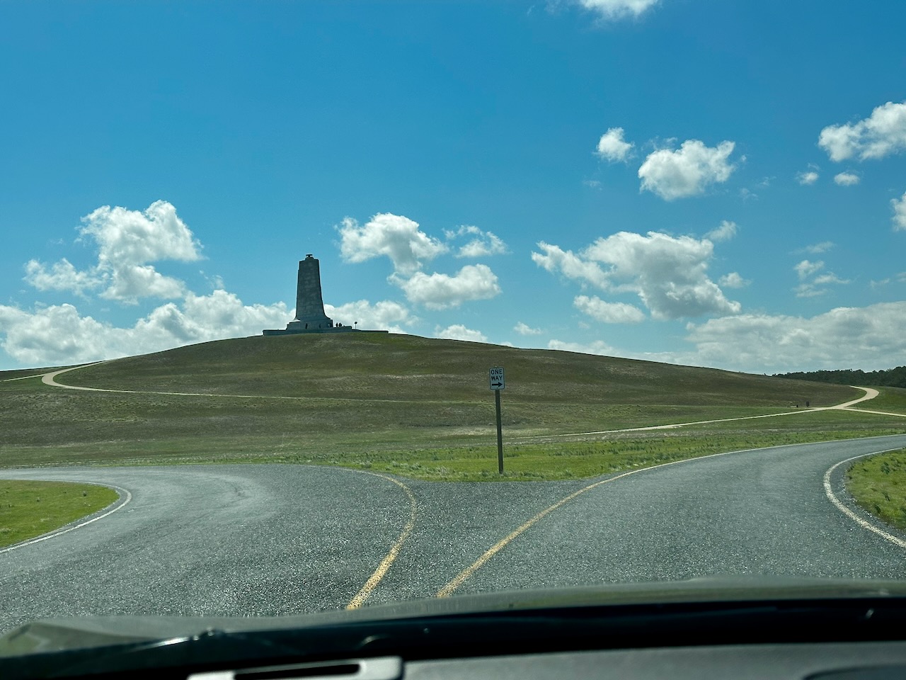 Entrance road at Wright Brothers National Memorial, with stone statue in distance on hill.