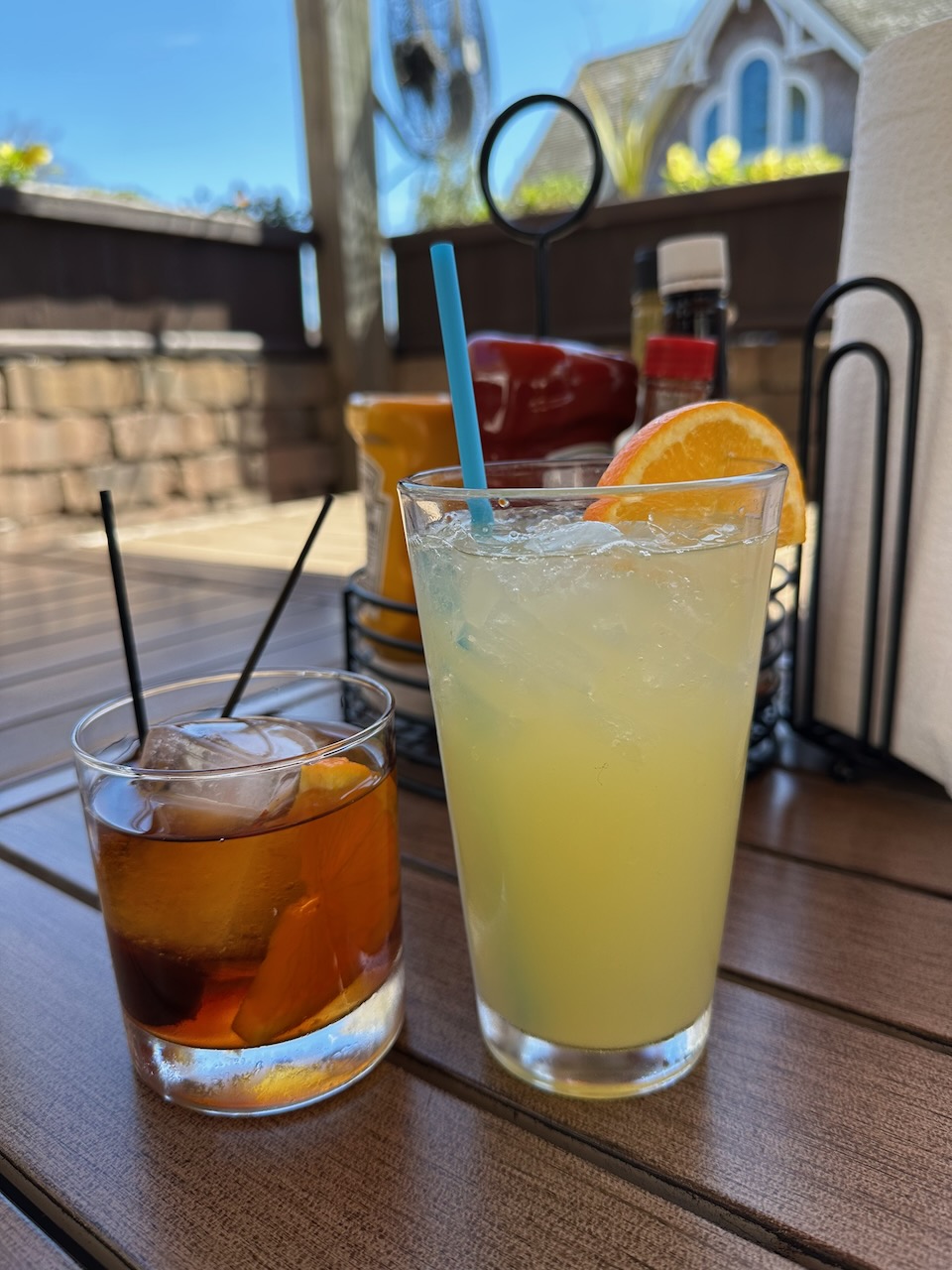 Two glasses with mixed drinks on table. An Old Fashioned is on the left, and a tropical-flavored drink on the right.