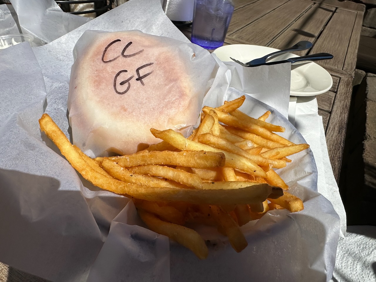 Crabcake wrapped in paper, with side of fries, all served in basket.