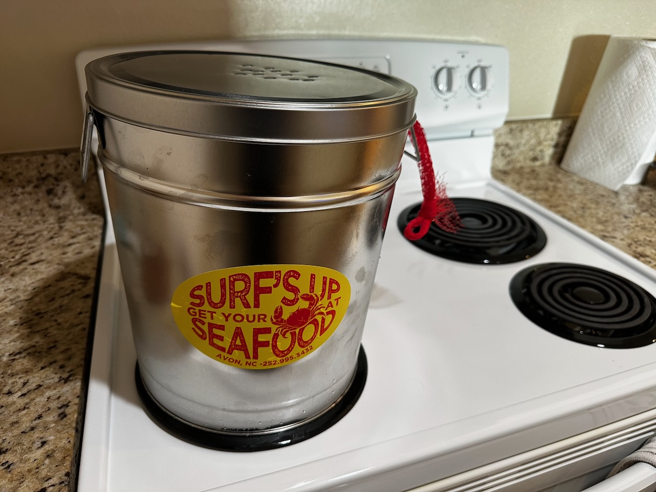 Clam bake tin on stove, with Surf’s up Seafood Market sticker on tin.