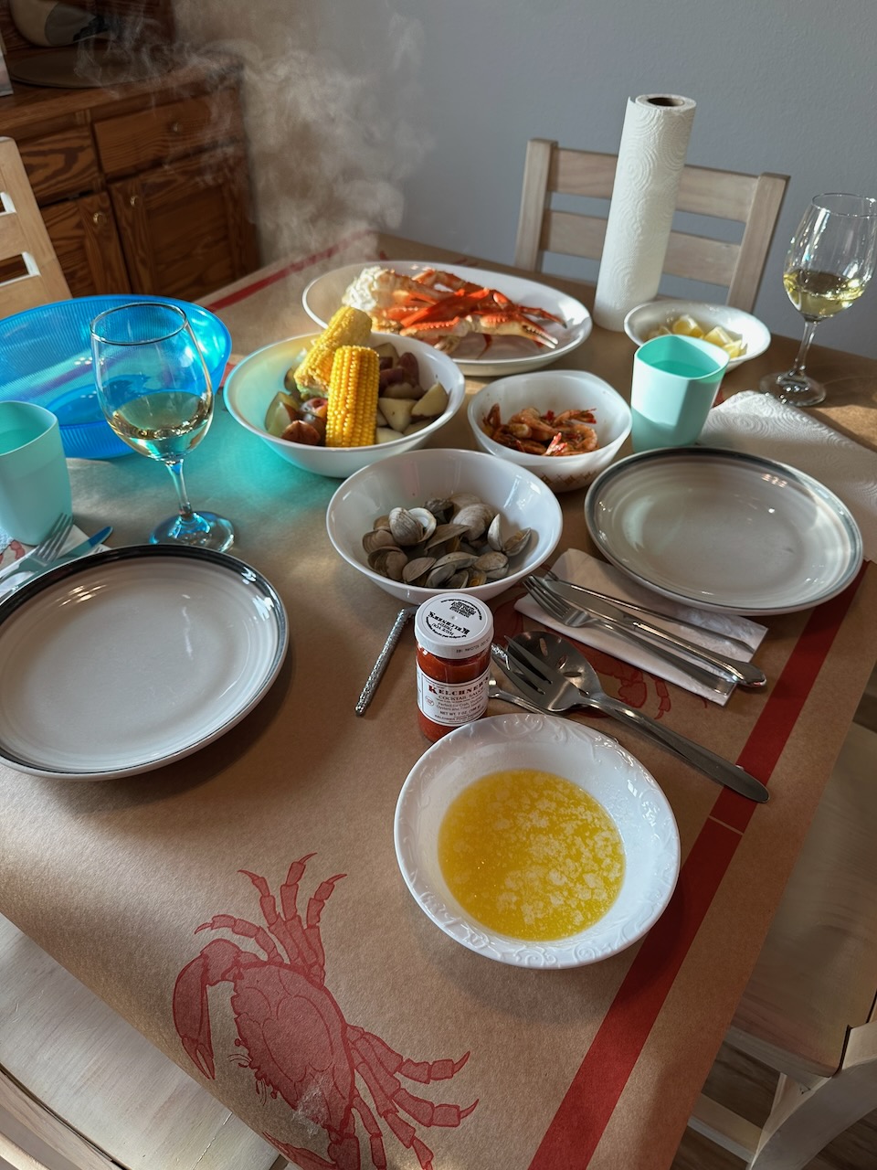 Table with plates, silverware, condiments, and bowls filled with seafood.