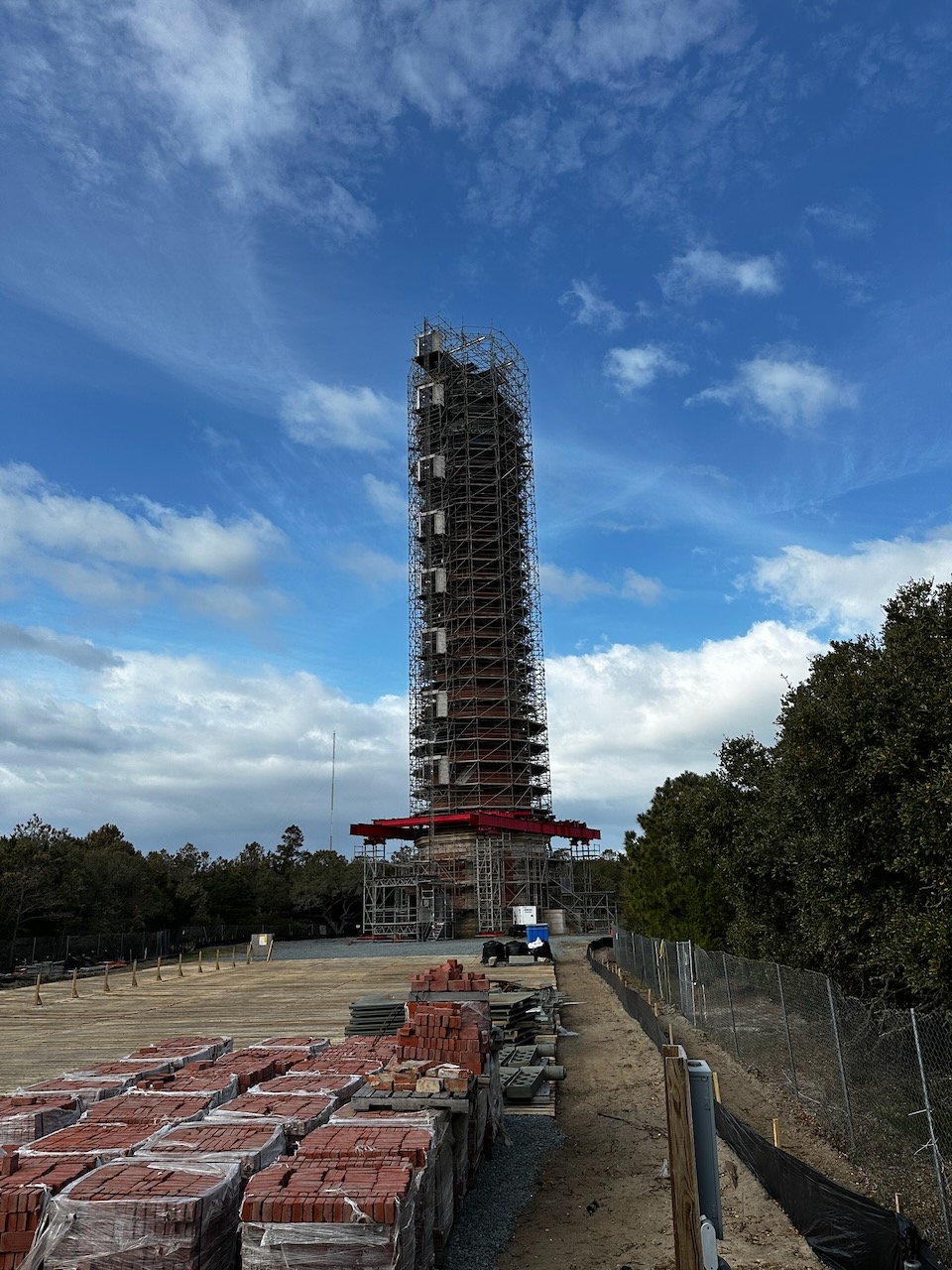 Cape Hatteras Light surrounded by scaffolding, with construction materials in the foreground.