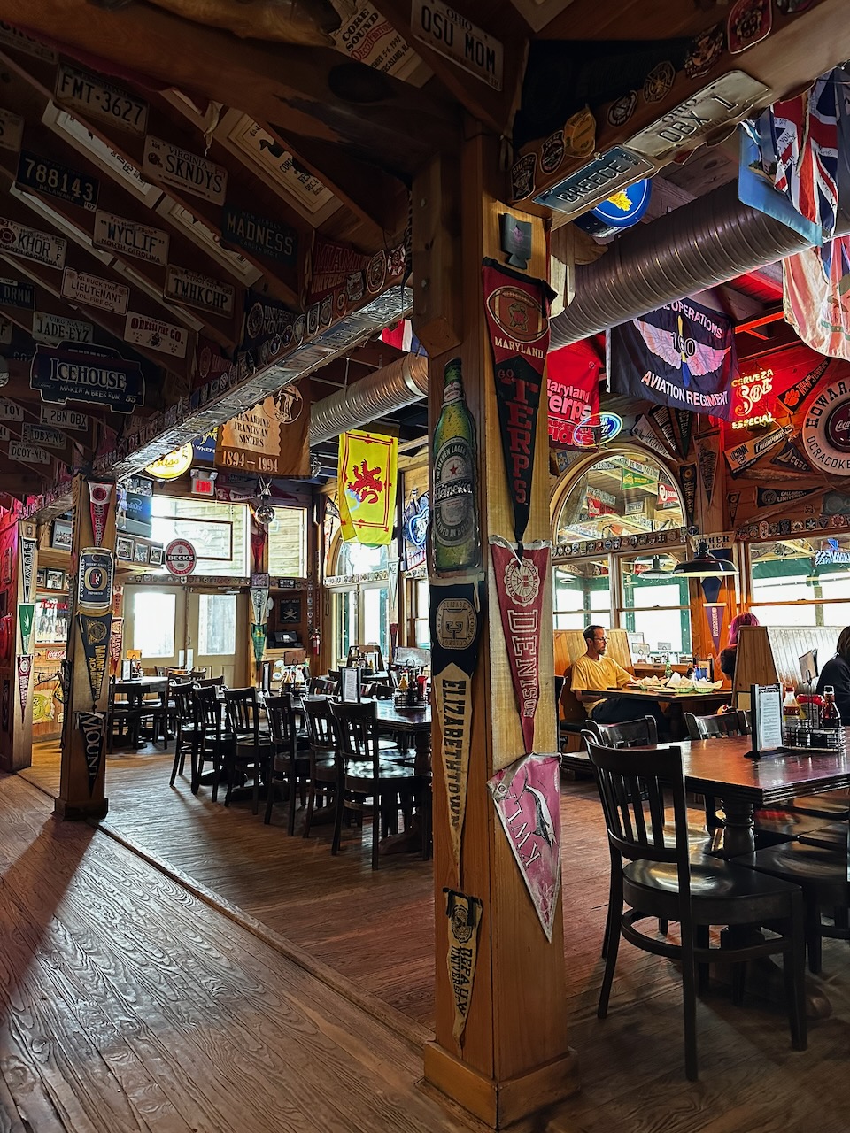 Interior of Howard's Pub and Raw Bar, with license plates and college banners hanging on walls.
