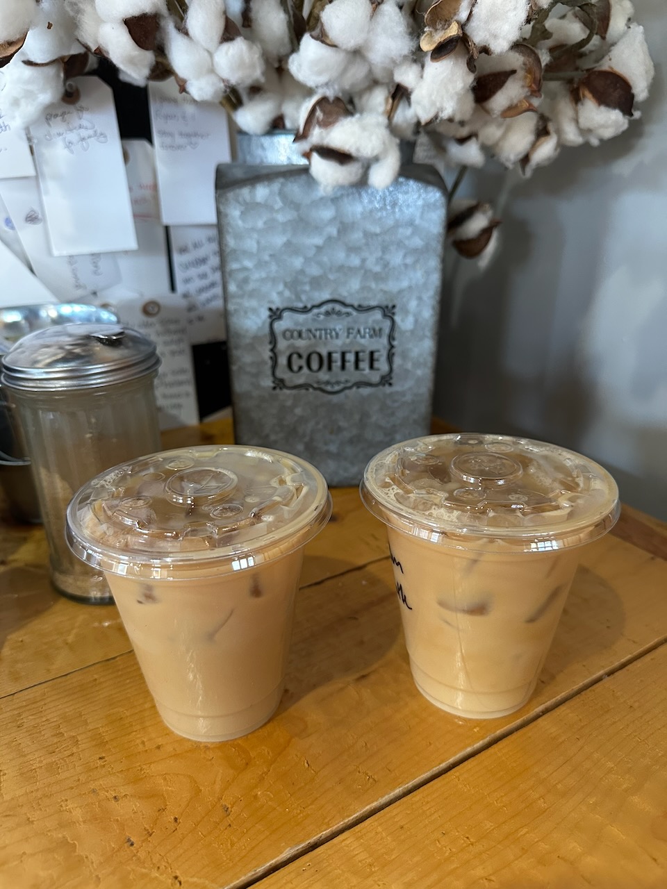 Iced almond milk latte and iced oat milk latte on wooden counter.