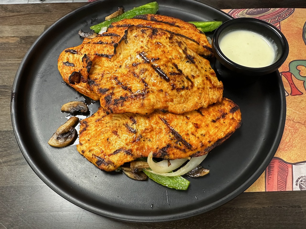 Mexican grilled chicken on black plate.
