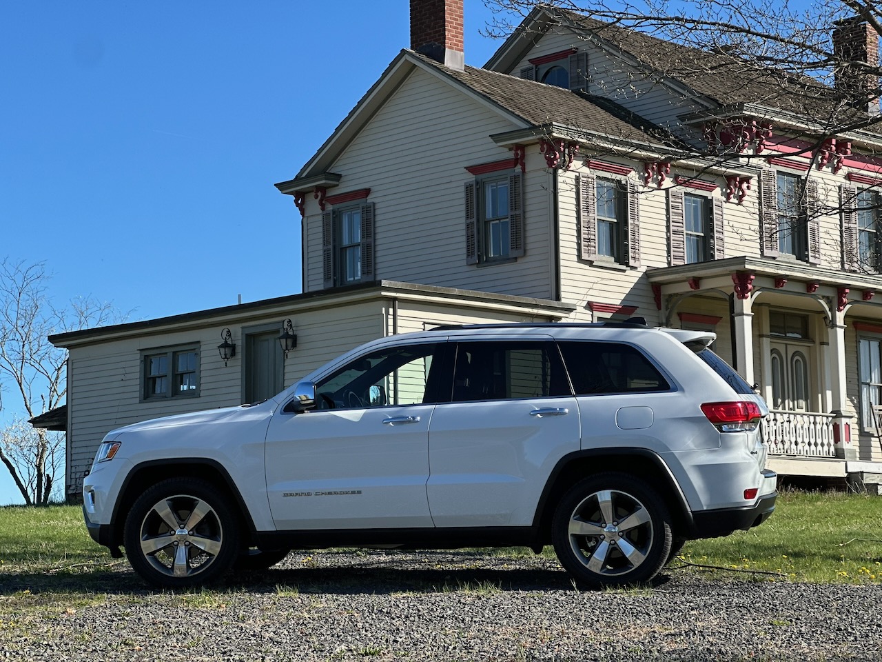 2014 Jeep Grand Cherokee parked in front of large two-story historic home.
