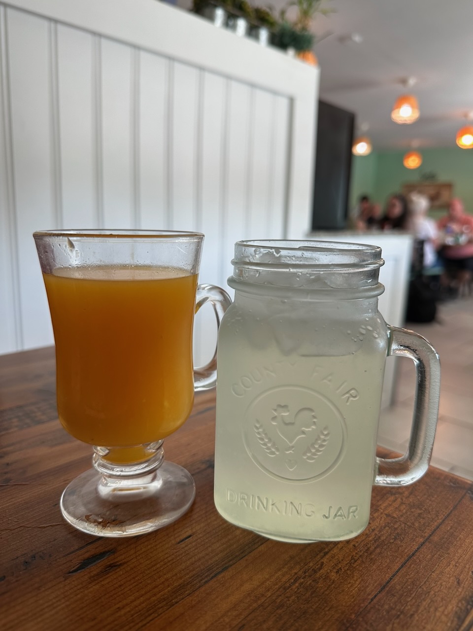 Glasses of homemade lemonade and freshly squeezed orange juice on table.