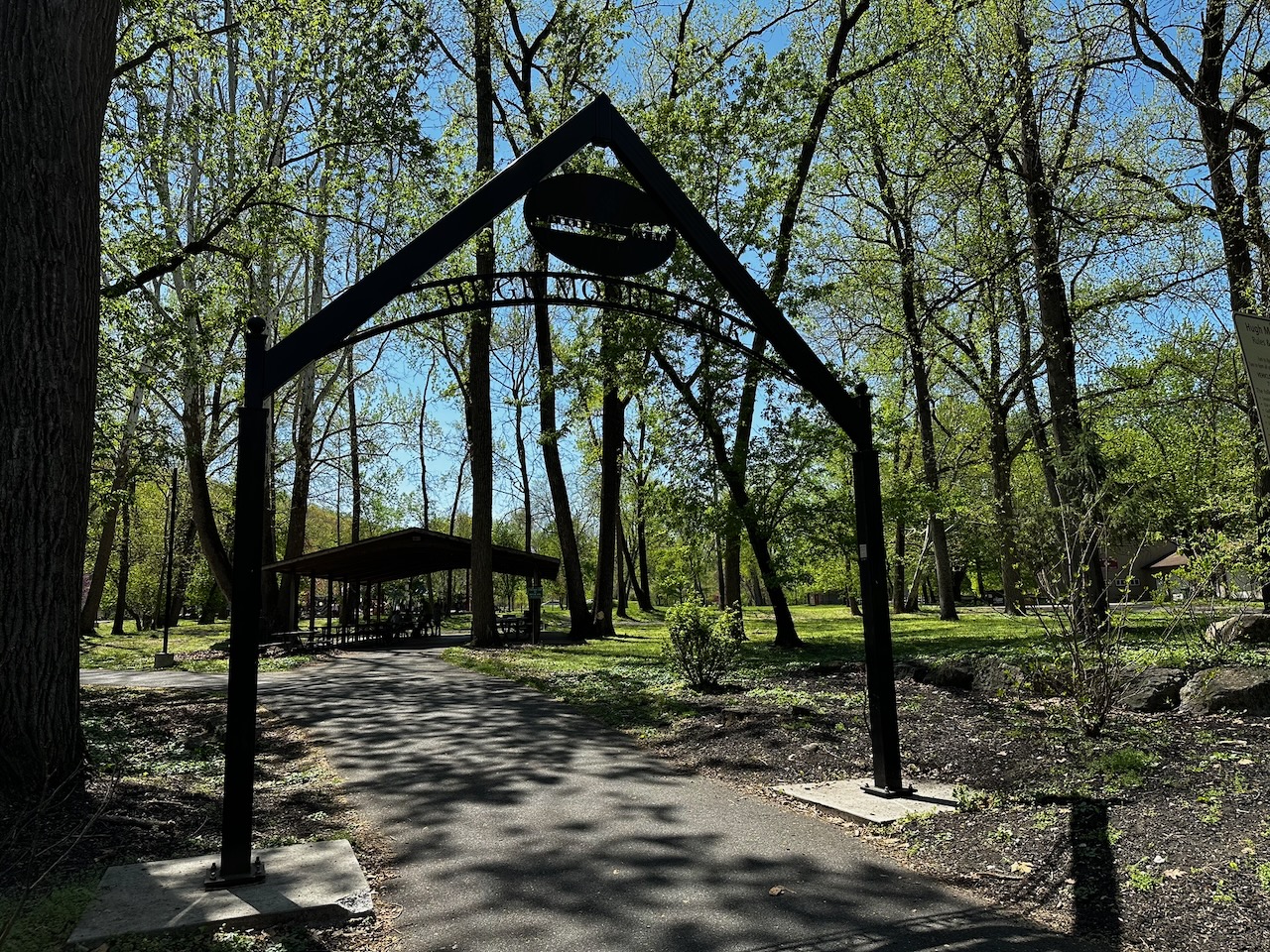 Entrance to Hugh Moore Park, with trees on either side of entrance.
