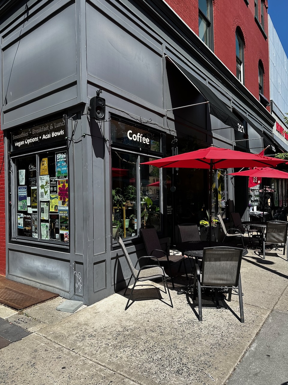 Exterior of Terra Cafe, with patio tables and red umbrellas on sidewalk in front of cafe.